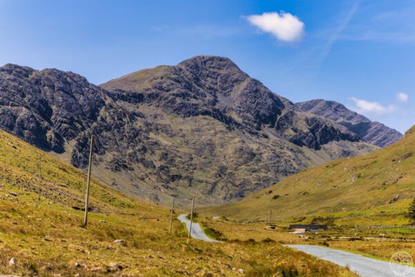 Road to the Twelve Bens A winding road leading to a stone bridge with the sharp peaks of the Twelve Bens mountains in Connemara, County Galway.