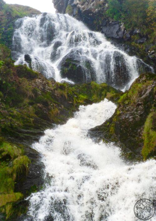 Turbulent Assaranca Waterfall near Ardara, County Donegal, featuring powerful white water crashing over mossy rocks on the Wild Atlantic Way.