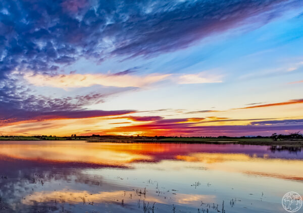A vibrant sunset with pink and orange clouds reflecting in the still waters of Urlaur Lough, County Mayo.